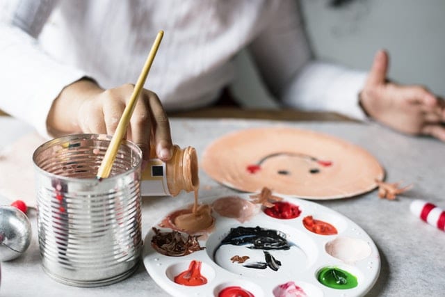 copil care picteaza cu pensula paleta de culori
