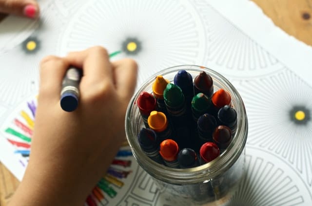 copil care deseneaza cu creioane colorate